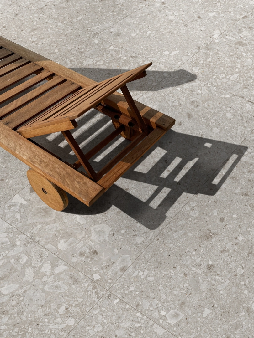 Wielkoformatowy gres Ragno Realstone Ceppo efekt terrazzo w salonie z kominkiem