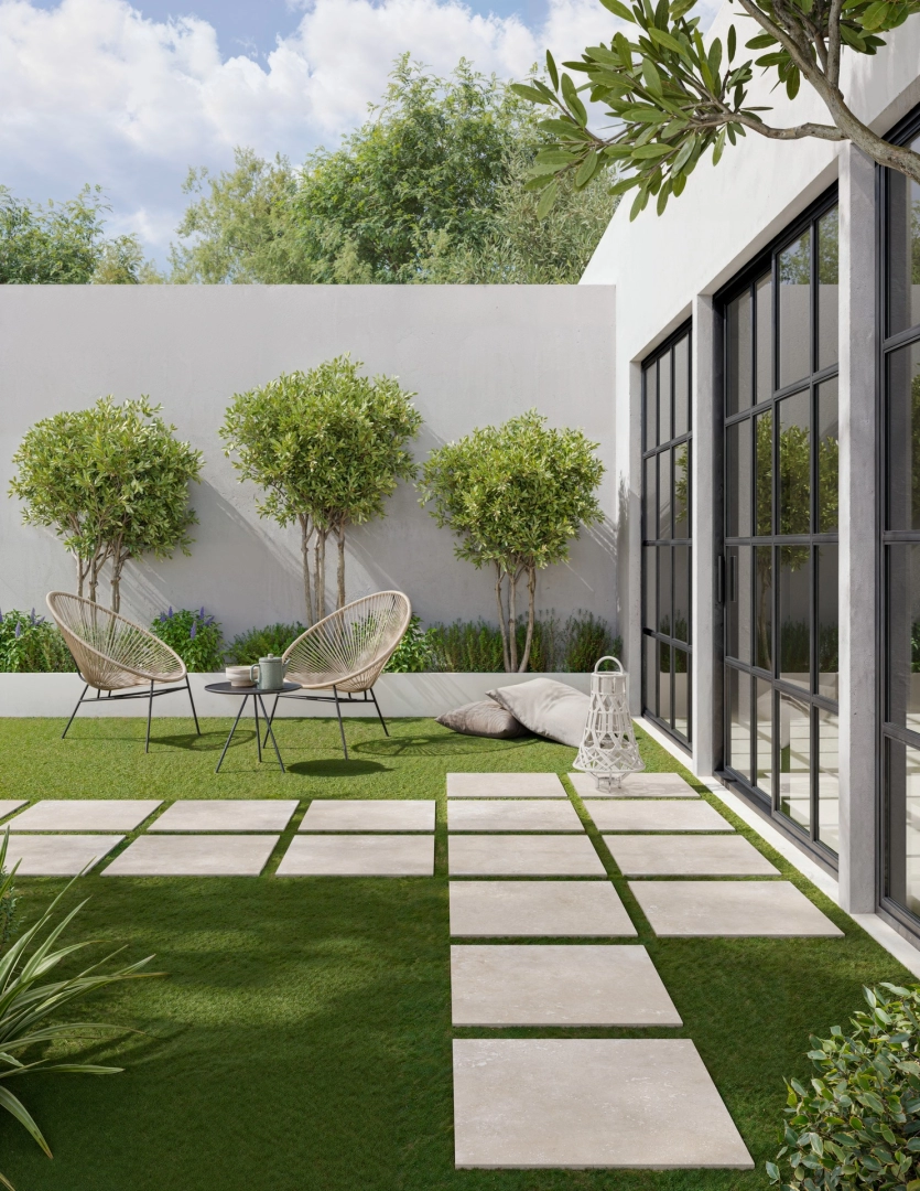 Wielkoformatowy gres Ragno Realstone Travertino efekt kamień w salonie z widokiem na ogród