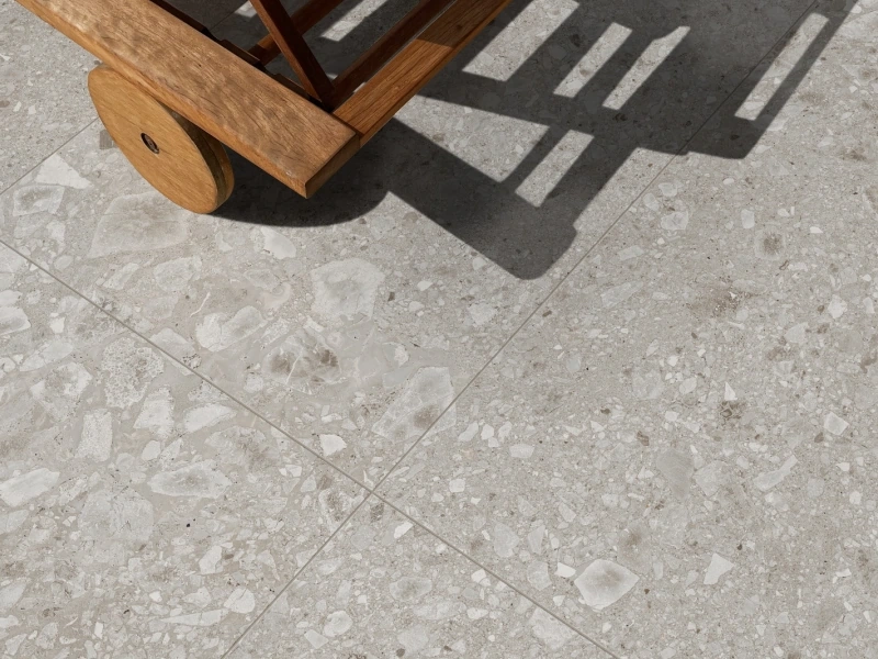 Wielkoformatowy gres Ragno Realstone Ceppo efekt terrazzo w salonie z kominkiem